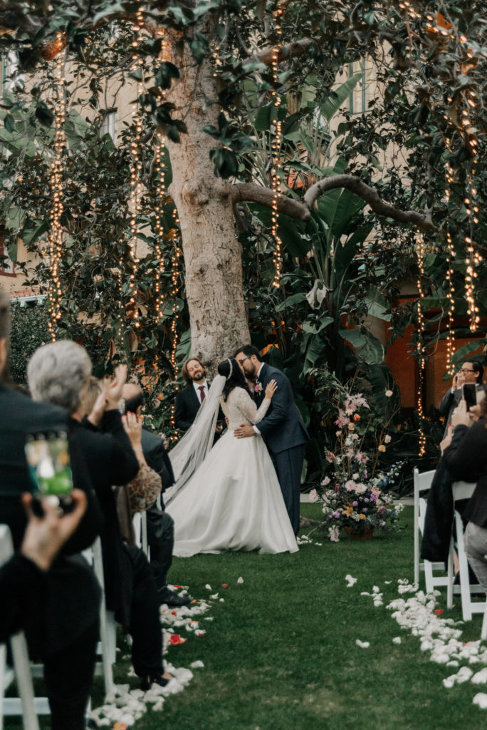 bride and groom kissing in front of tree