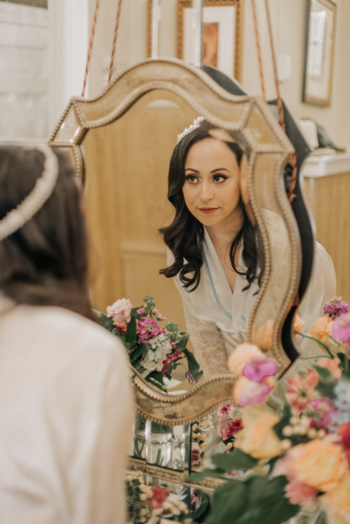 bride looking in mirror getting ready whimsical flowers